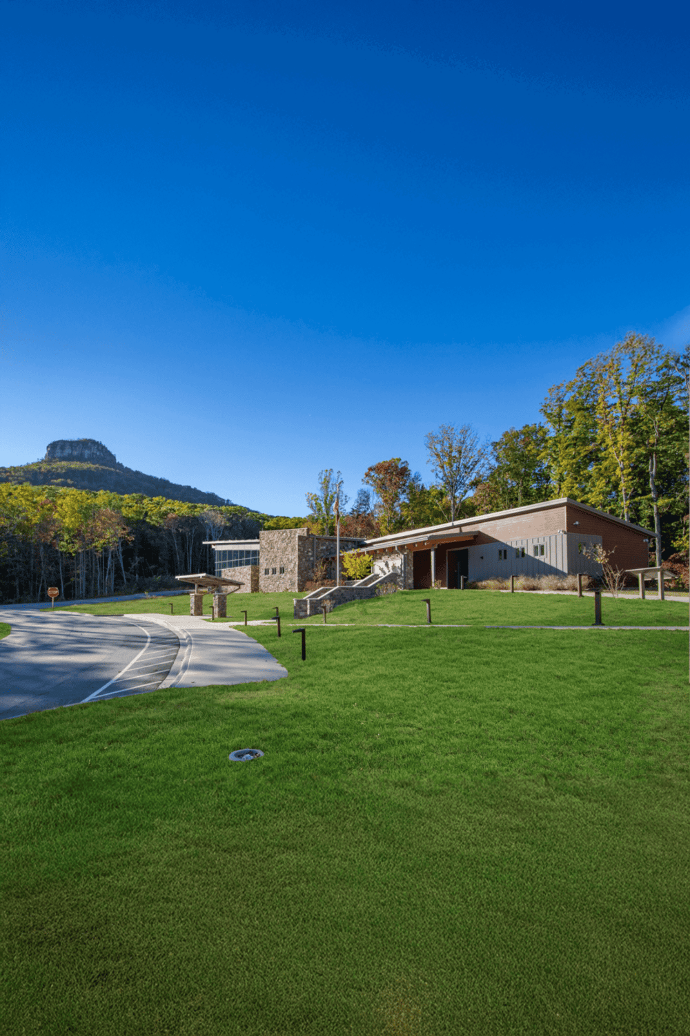 Modern travel assistance facility surrounded by green landscape and scenic mountain views.