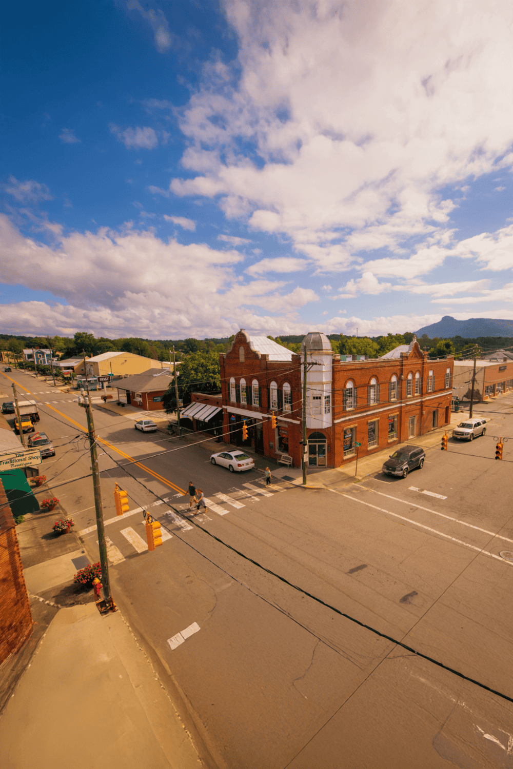 Charming small-town street with historic brick buildings and scenic mountain views in the background.