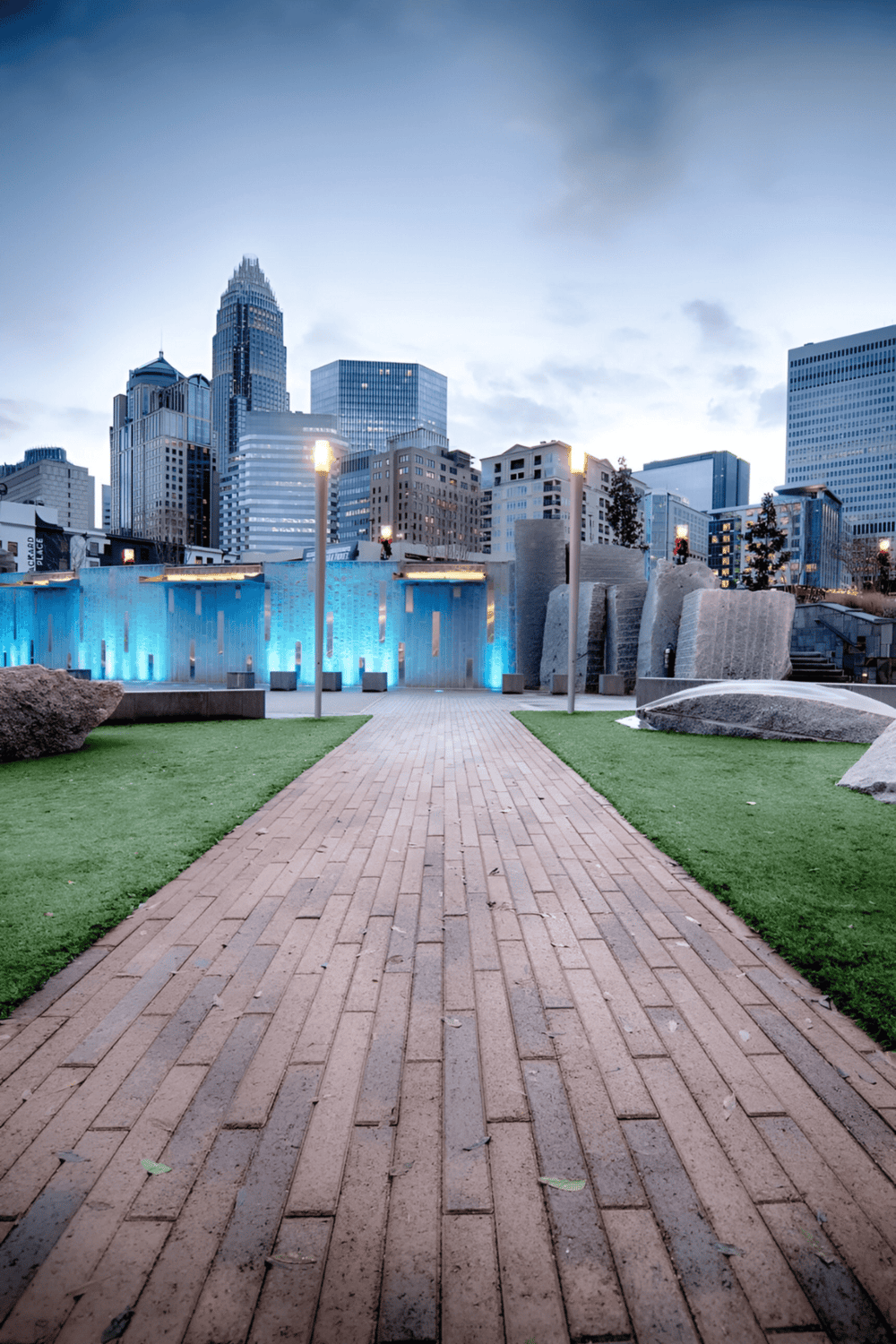 Modern cityscape with lush park, illuminated fountain, and skyscrapers in downtown Charlotte, North Carolina.