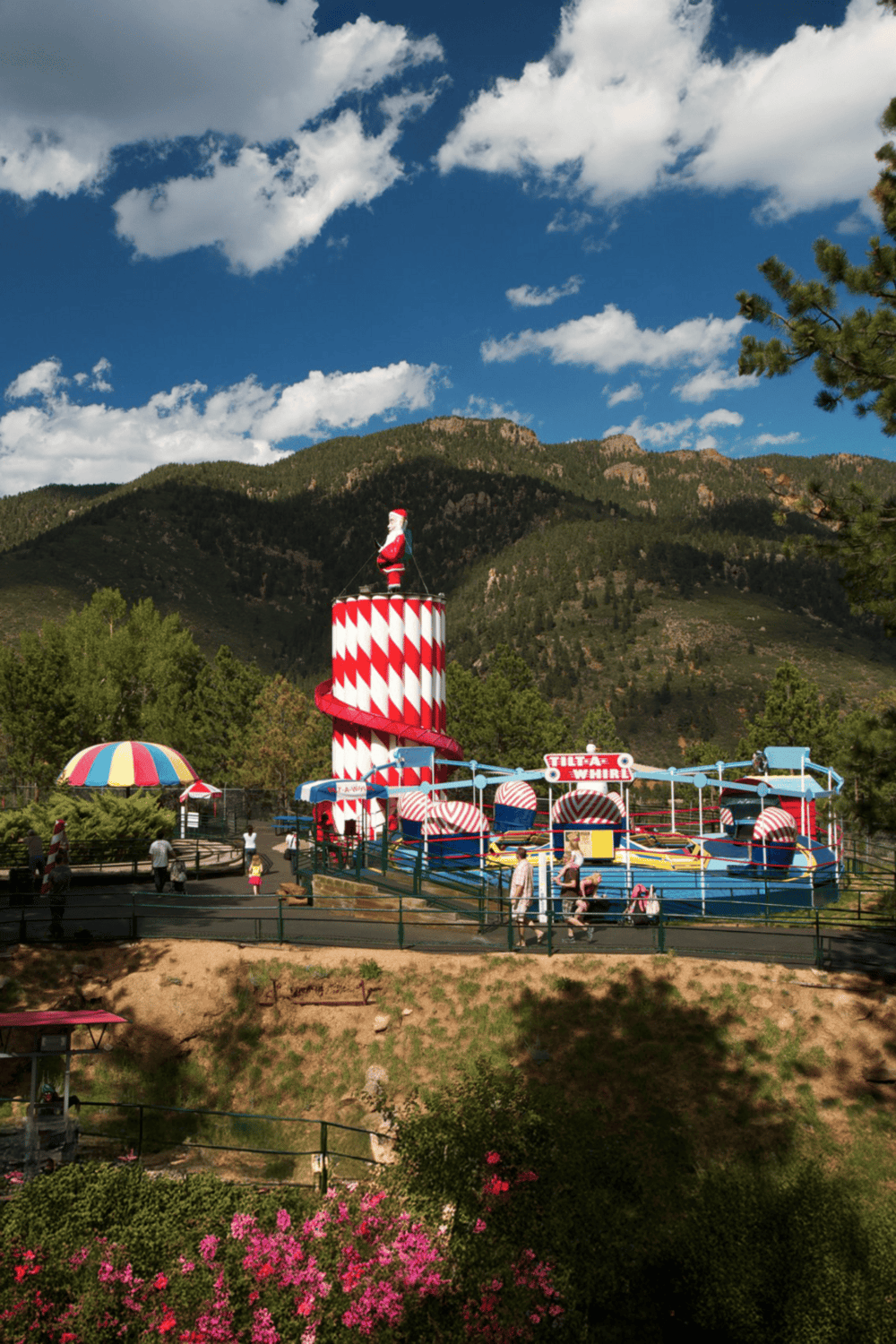 Colorful amusement park ride with Santa theme set against mountain backdrop.