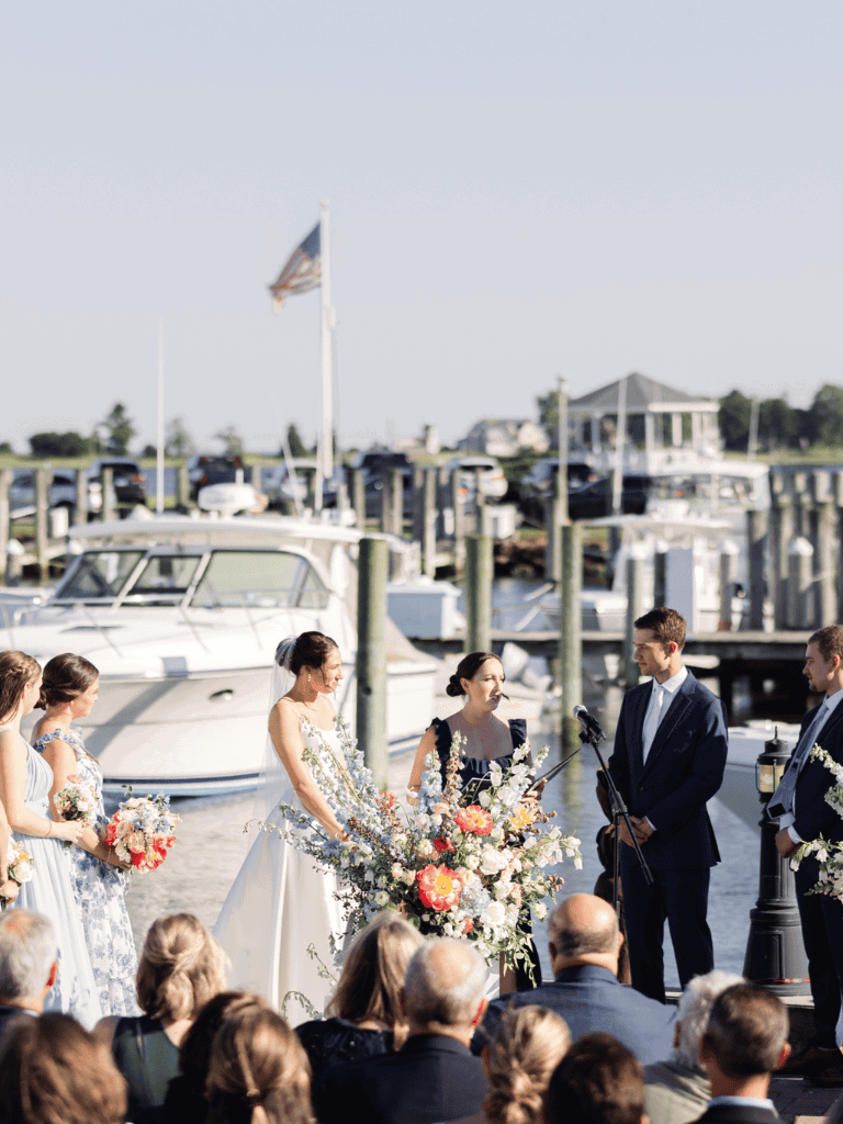 Bride and groom exchange vows by the marina during a seaside wedding ceremony.