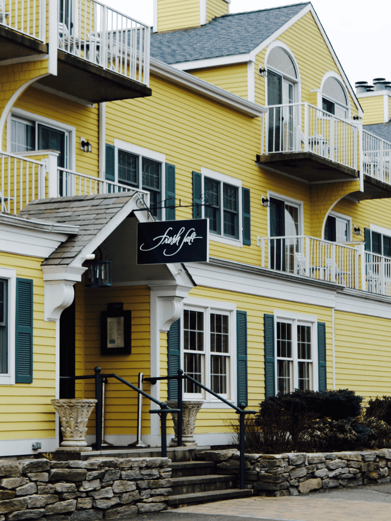 Yellow multi-story building with balconies and a black sign reading "Fresh Cafe".
