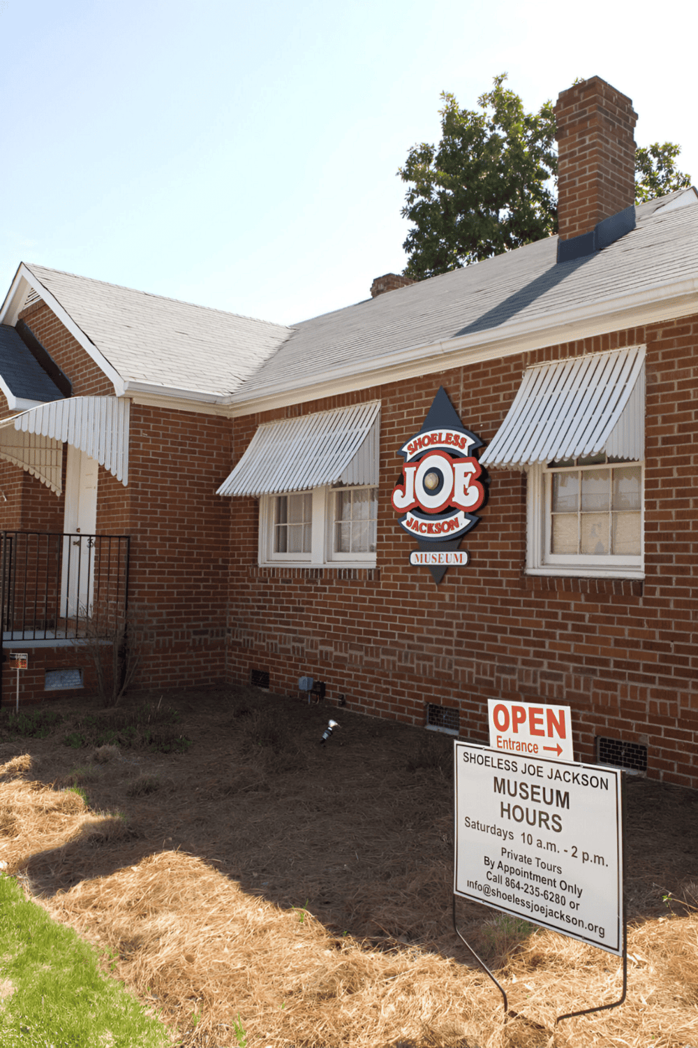Historic shoe repair shop building with signage for Shoeless Joe Jackson Museum, sunny day, brick exterior.