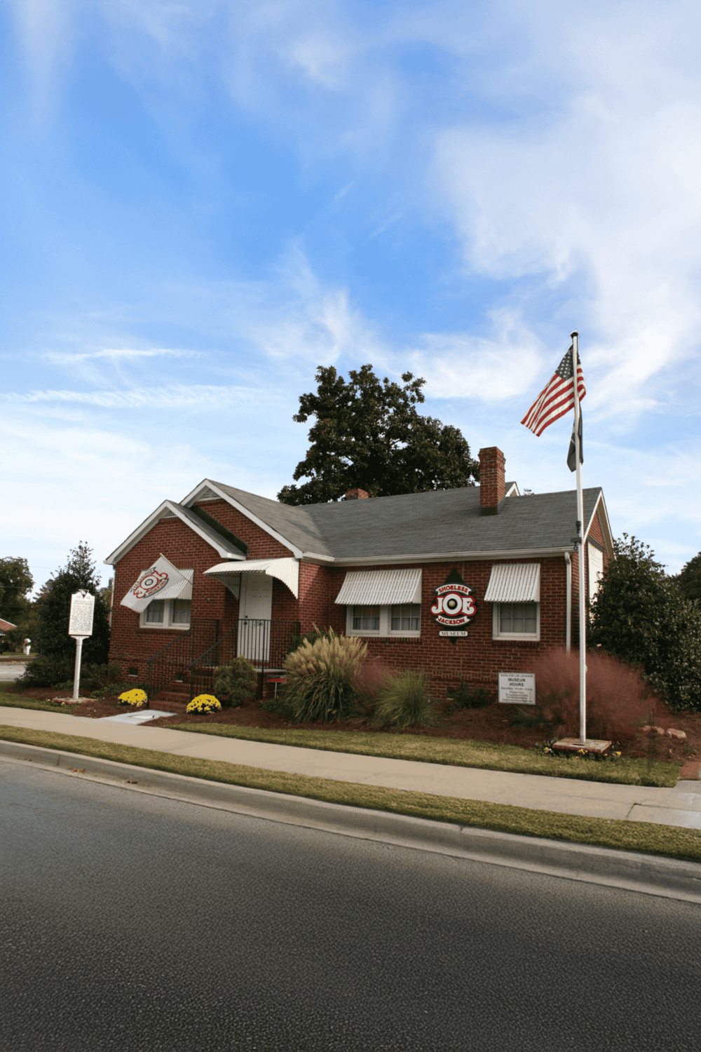 Victorian-style house with American flag and signage for Joe's Museum on a sunny day.