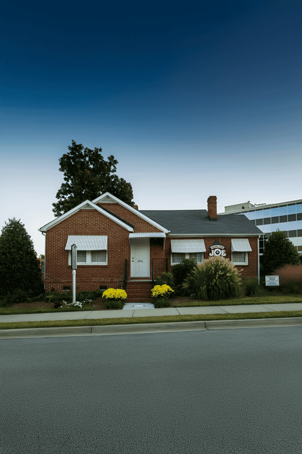 1. Cozy brick house with striped awnings and well-maintained front yard, highlights local neighborhood charm.