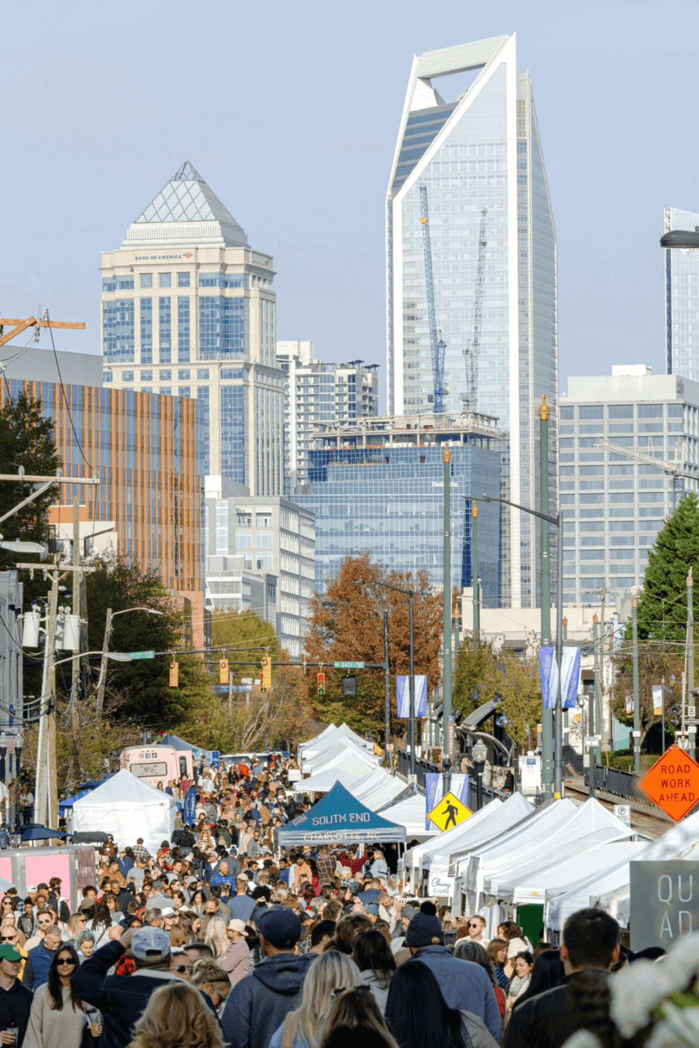 Crowd at outdoor event in downtown Charlotte, North Carolina, with skyscrapers in background.