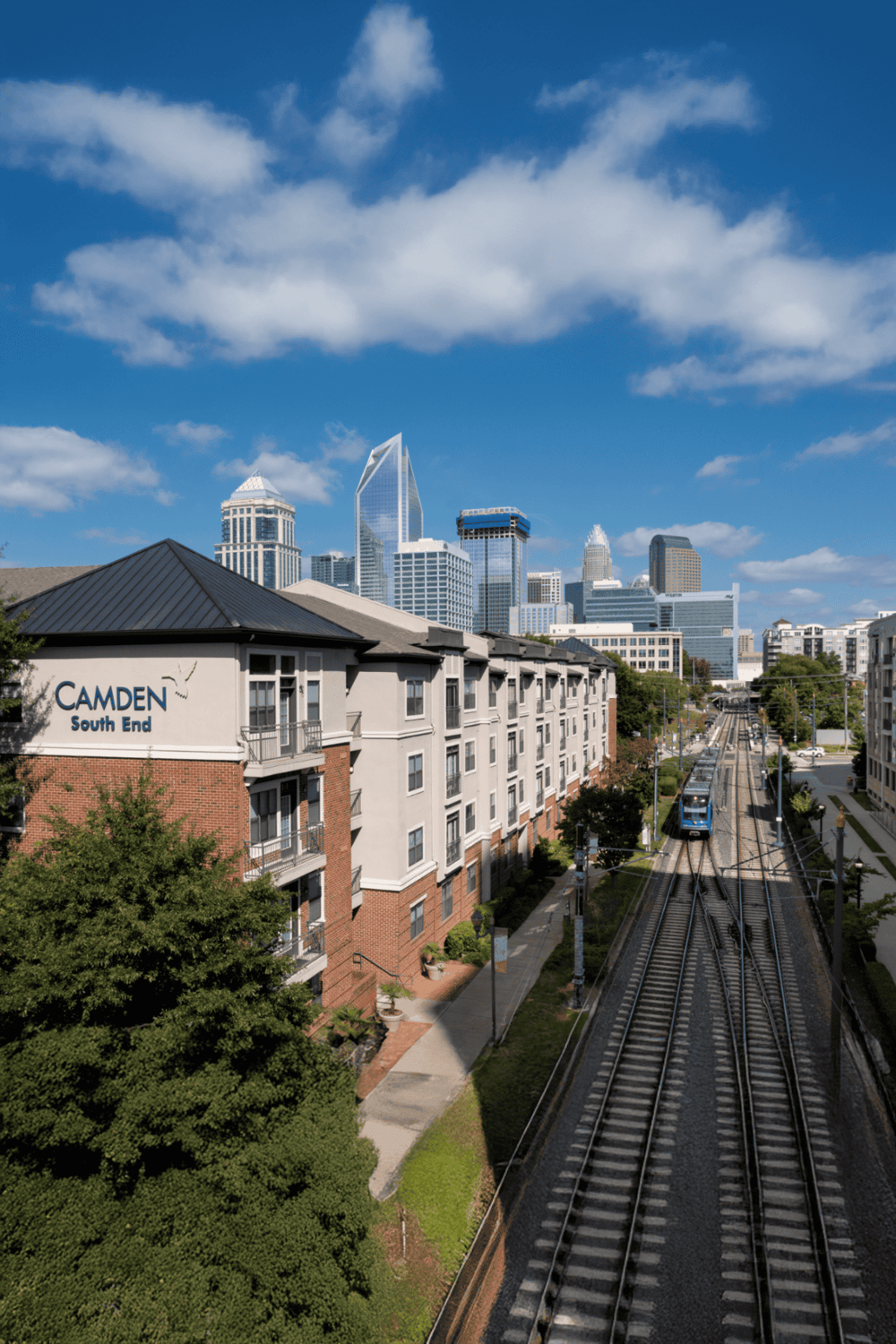 Modern urban skyline with residential buildings, train tracks, and cityscape in the background.