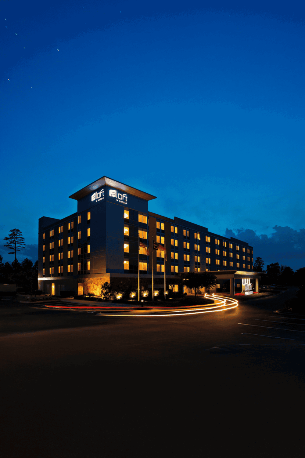 Modern hotel exterior nighttime lighting, illuminated "Aloft Hotels" sign, part of Quest For Directions.