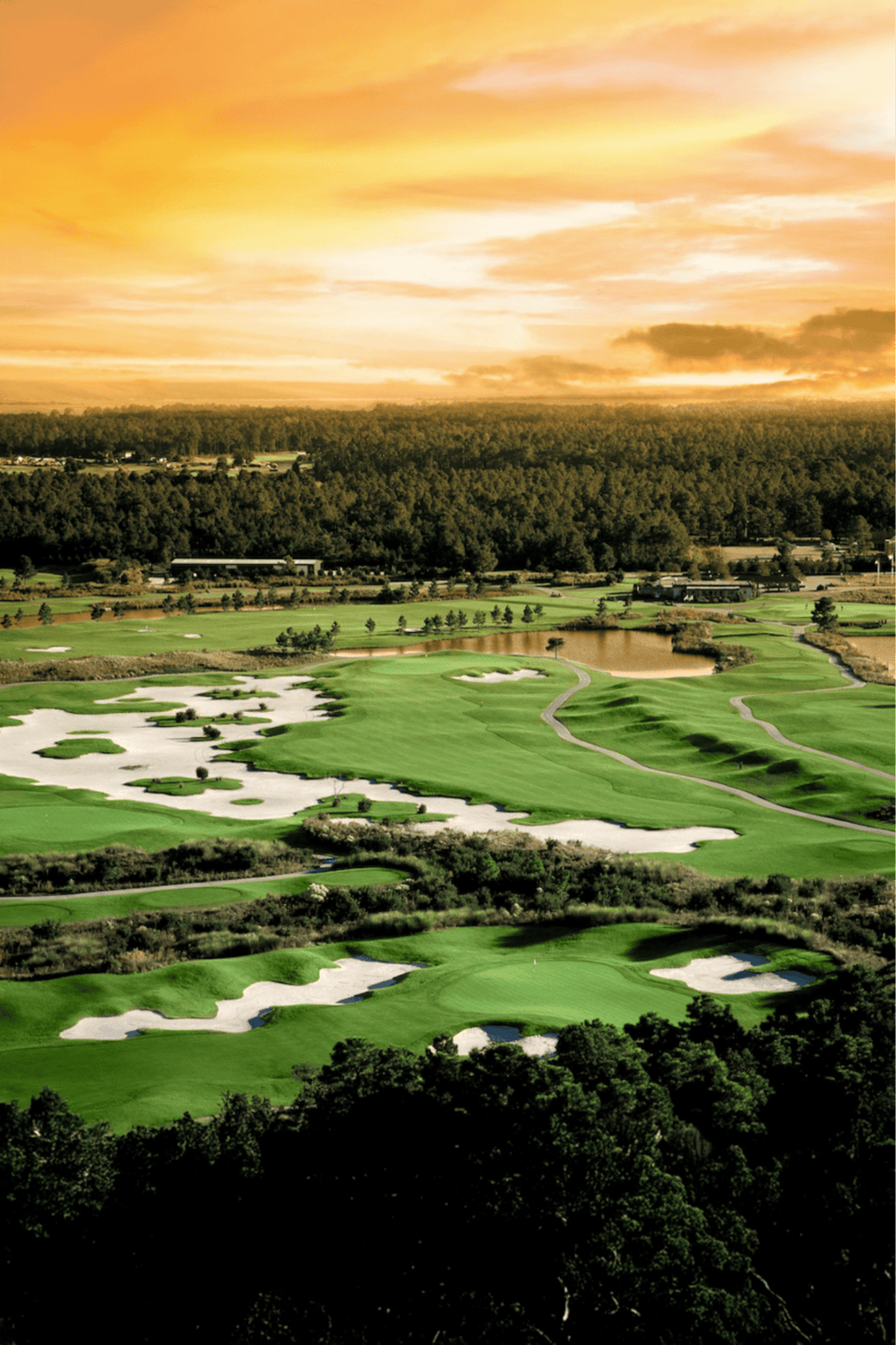 Vibrant golf course landscape at sunset, showcasing lush greens, sand traps, and water hazards.