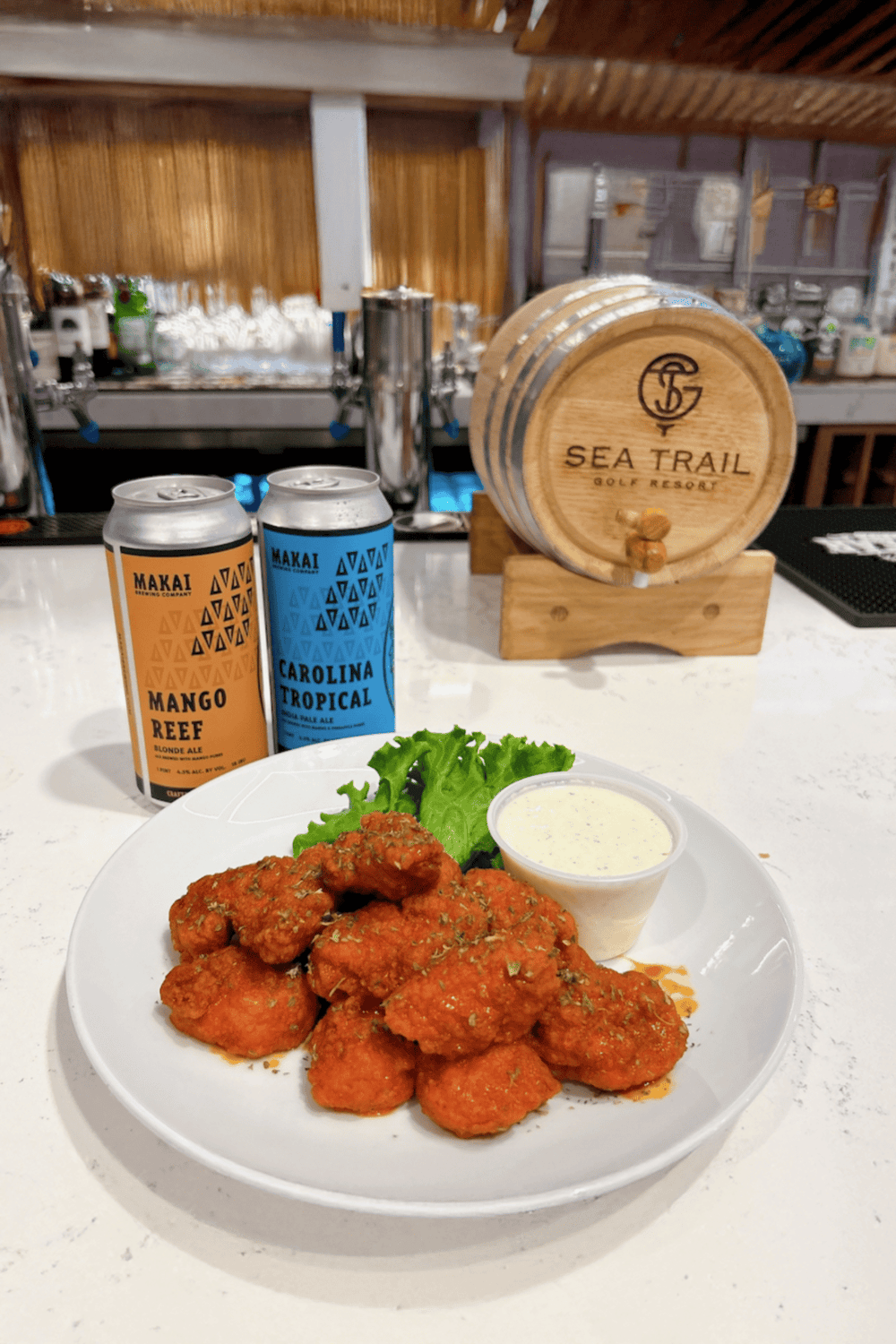 Crispy chicken wings with dipping sauce at Sea Trail Golf Resort bar, featuring craft beer options.