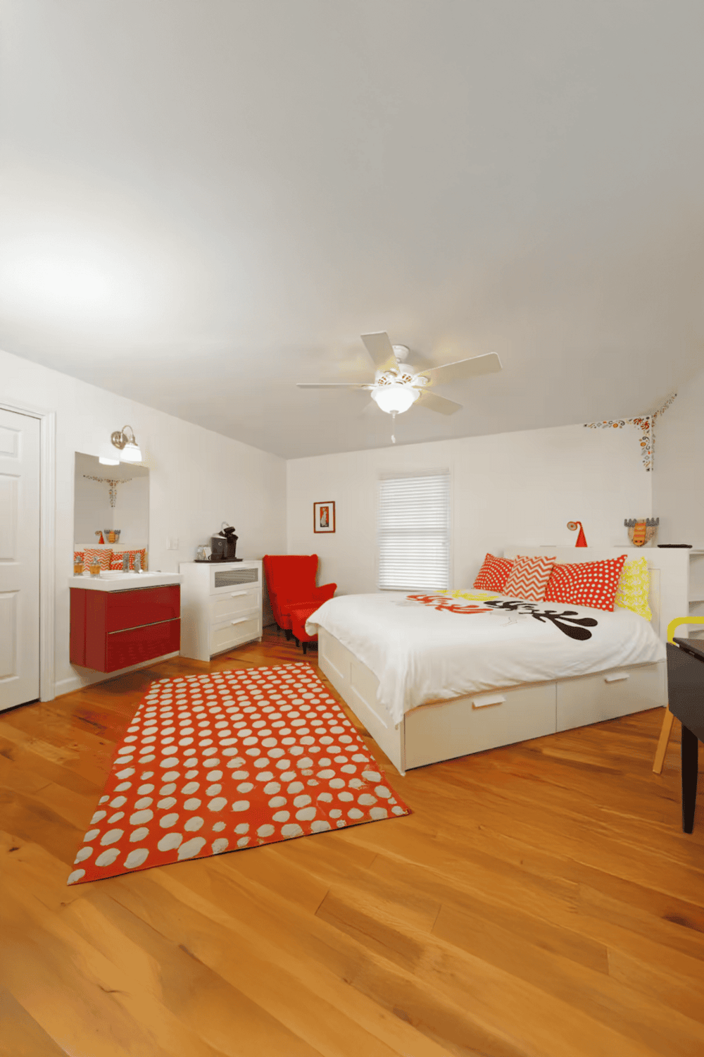 Cozy bedroom with colorful decor and hardwood floors, perfect for relaxing stays.