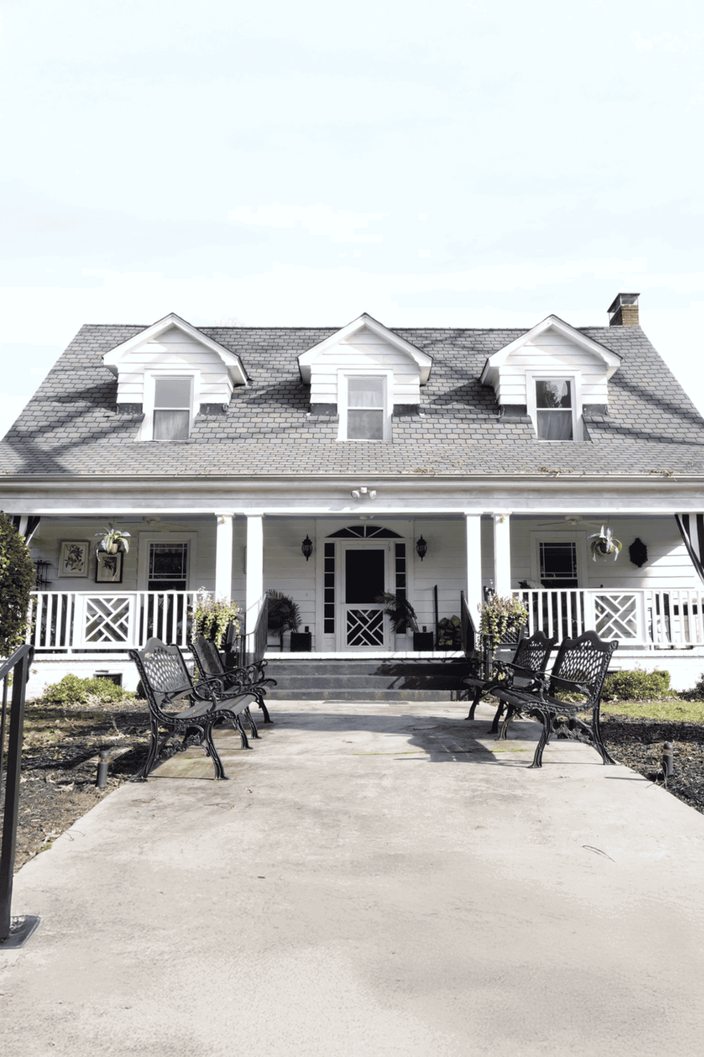Charming white house with porch and black benches, perfect for neighborhood exploration.
