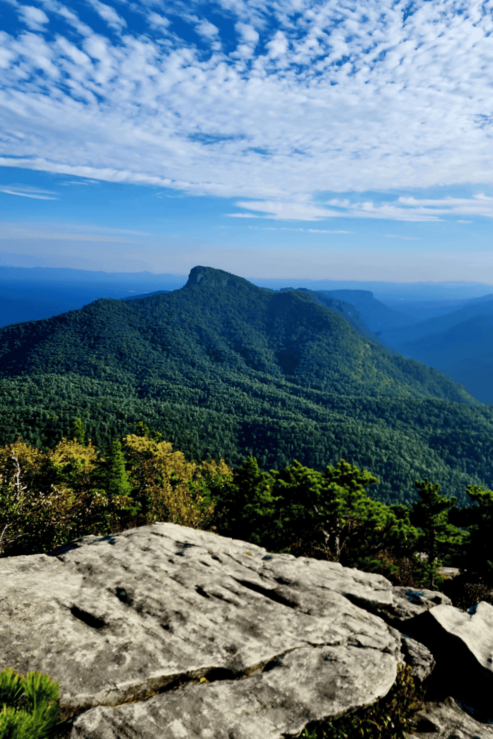Majestic mountain landscape with lush green forests and blue sky, perfect for outdoor adventure and nature exploration.
