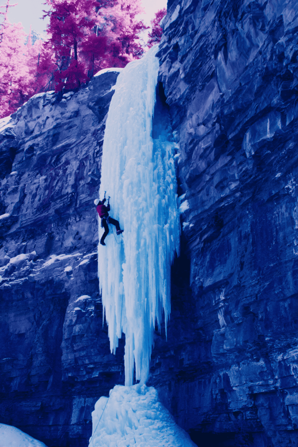 Ice climbing on a frozen waterfall in a scenic mountain landscape.