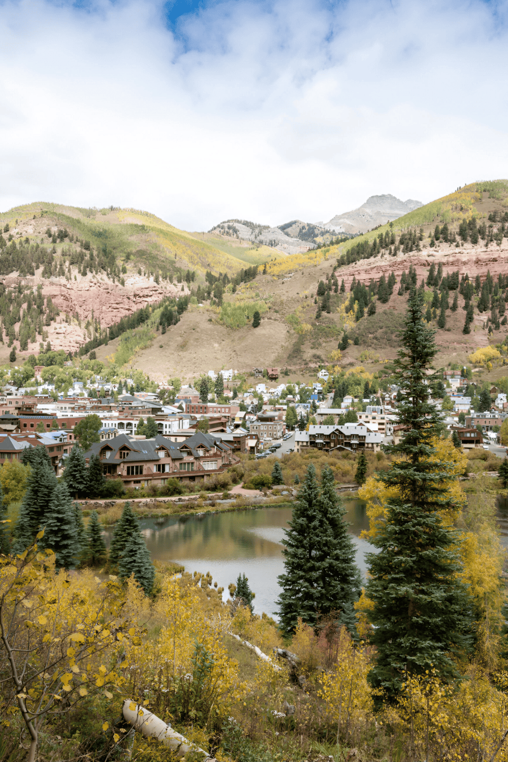 Vibrant mountain town with colorful hills, forested slopes, and a peaceful lake scenery.