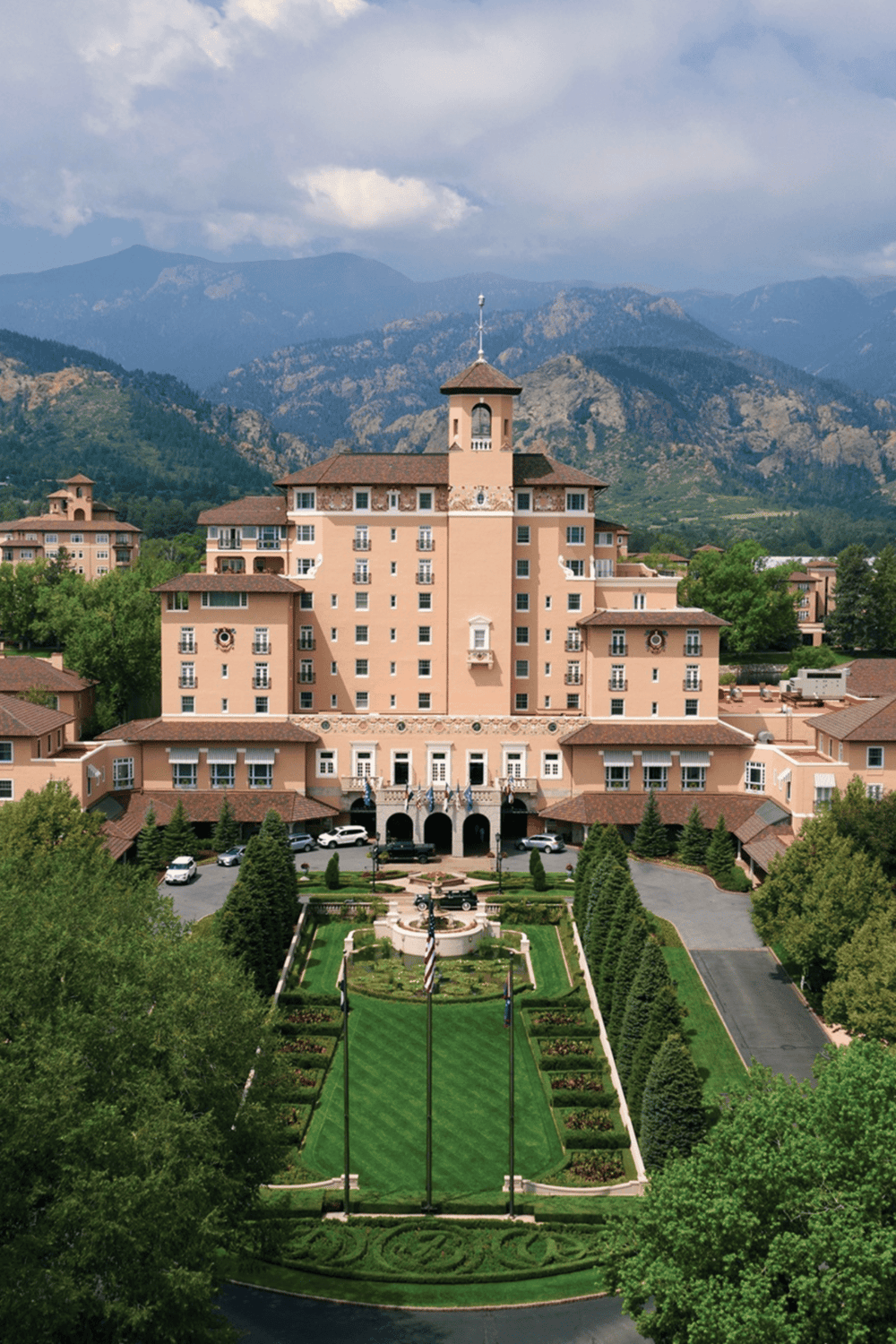 Elegant mountain resort with lush gardens and scenic backdrop of mountains and blue sky.