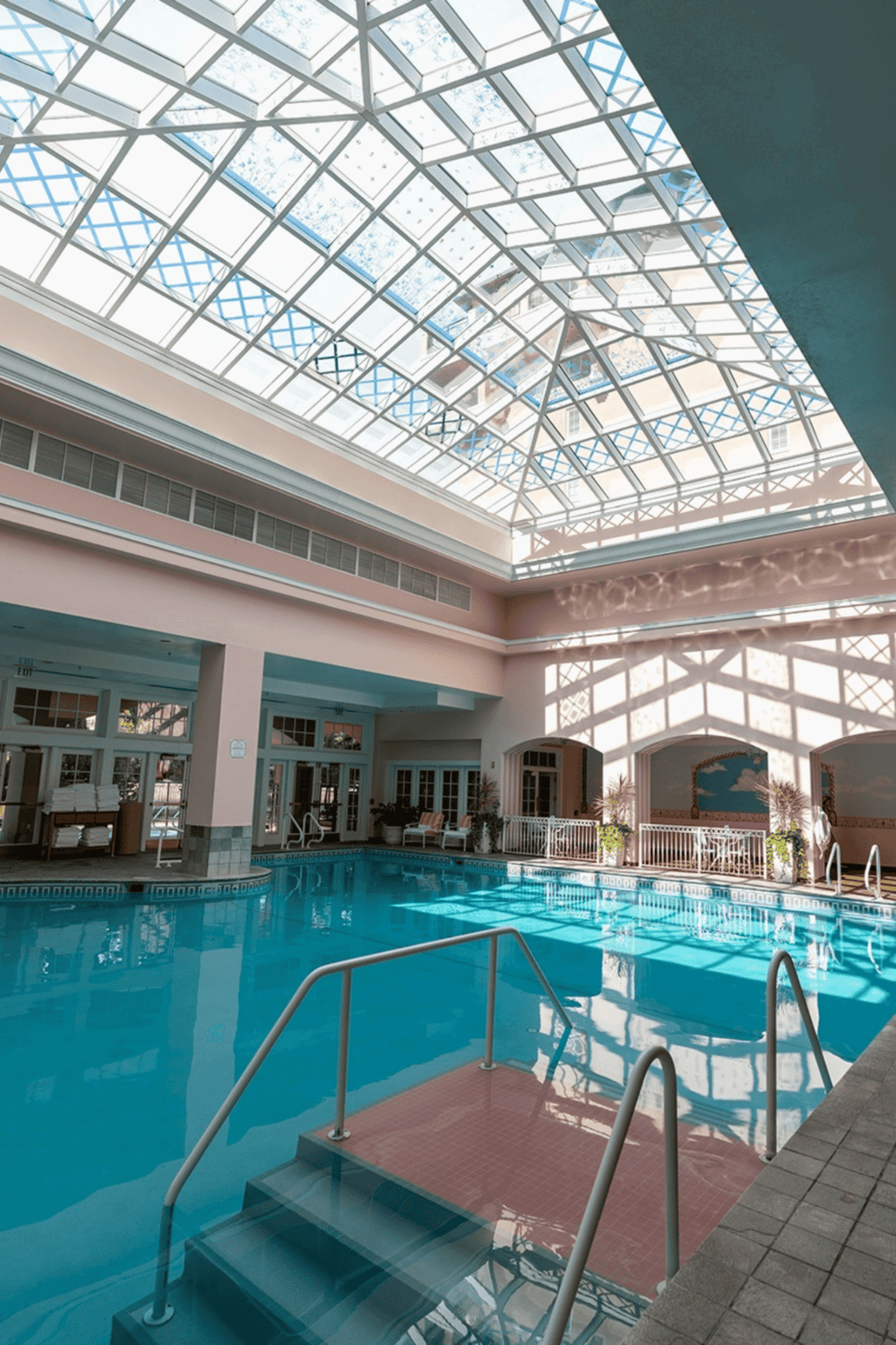 Indoor hotel pool with glass ceiling daylight illumination, relaxing spa atmosphere, and warm ambiance.