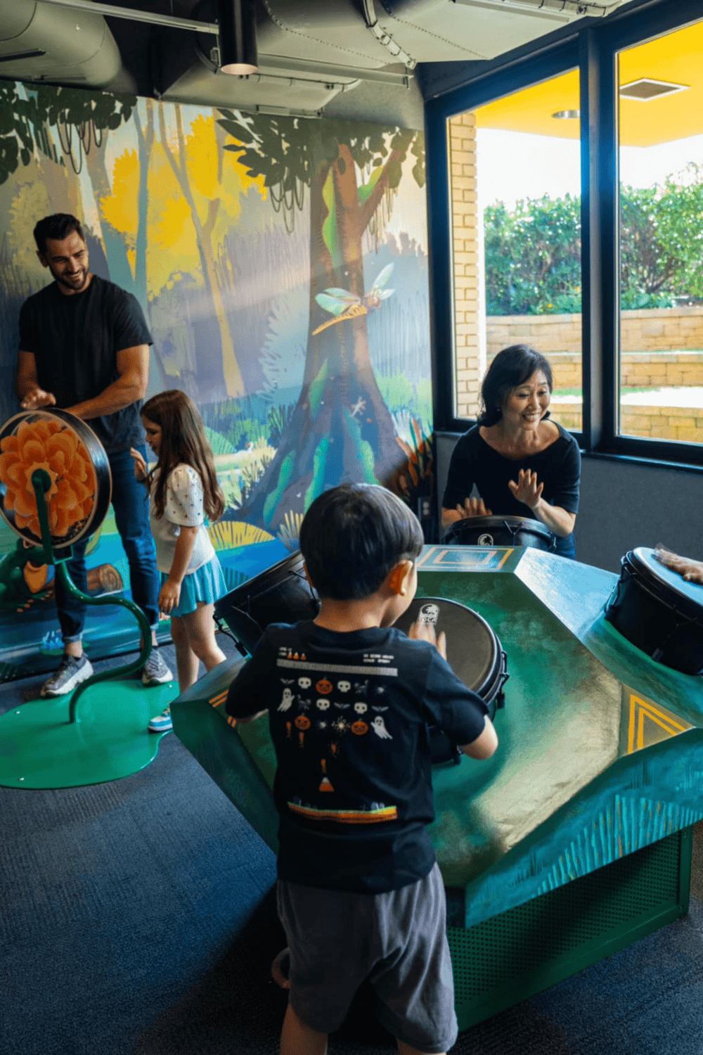 Interactive family fun at QuestForDirections escape room, with children playing drums and enjoying team activities.