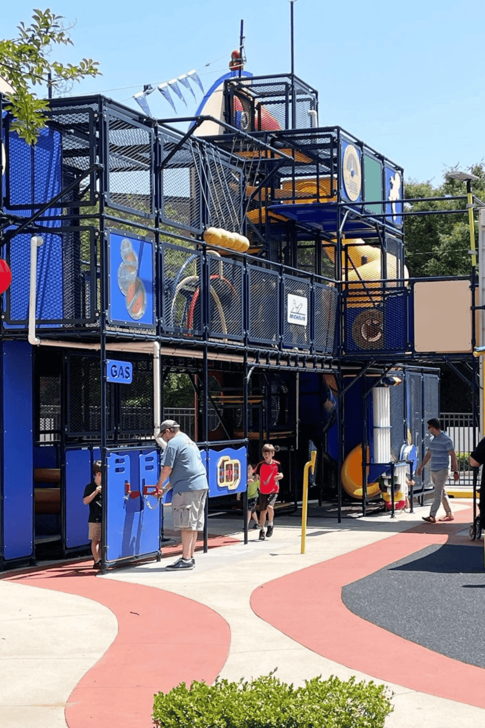 Colorful playground structure with slides and climbing areas for children, featuring safety fencing and a lively outdoor setting.