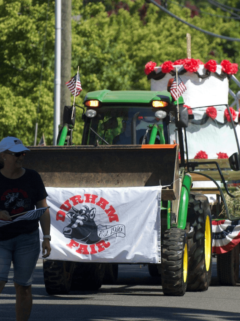 Colorful parade float decorated for the Durham Fair with tractor, flags, and floral accents.