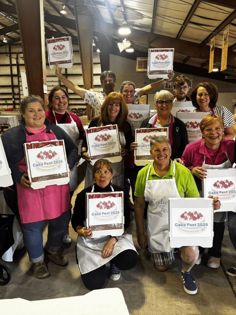 Caring group of bakers celebrating Cake Fest 2025 with handmade cake boxes, smiling and holding awards.