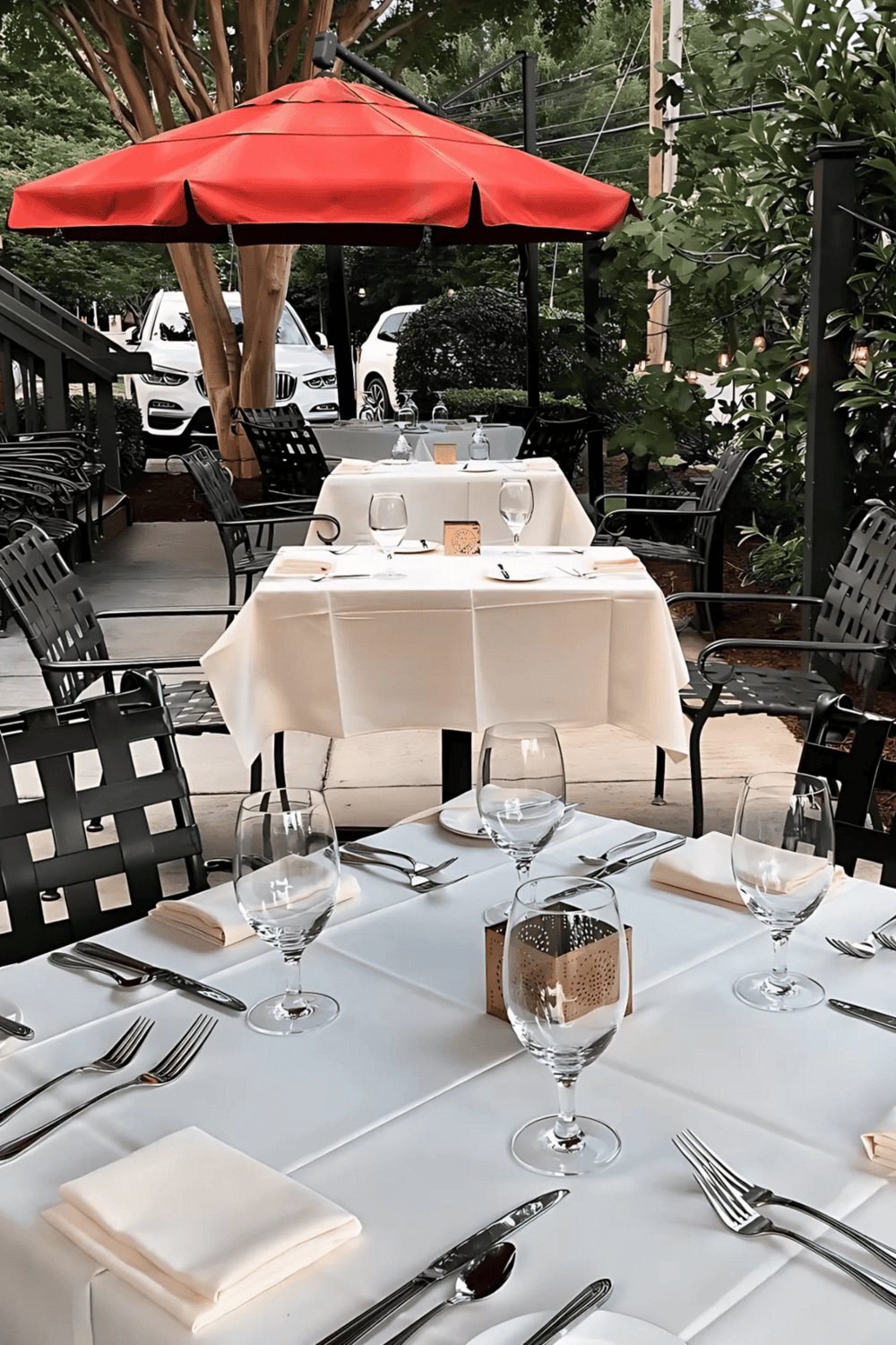 Outdoor fine dining restaurant with elegant table settings and lush greenery for a memorable culinary experience.