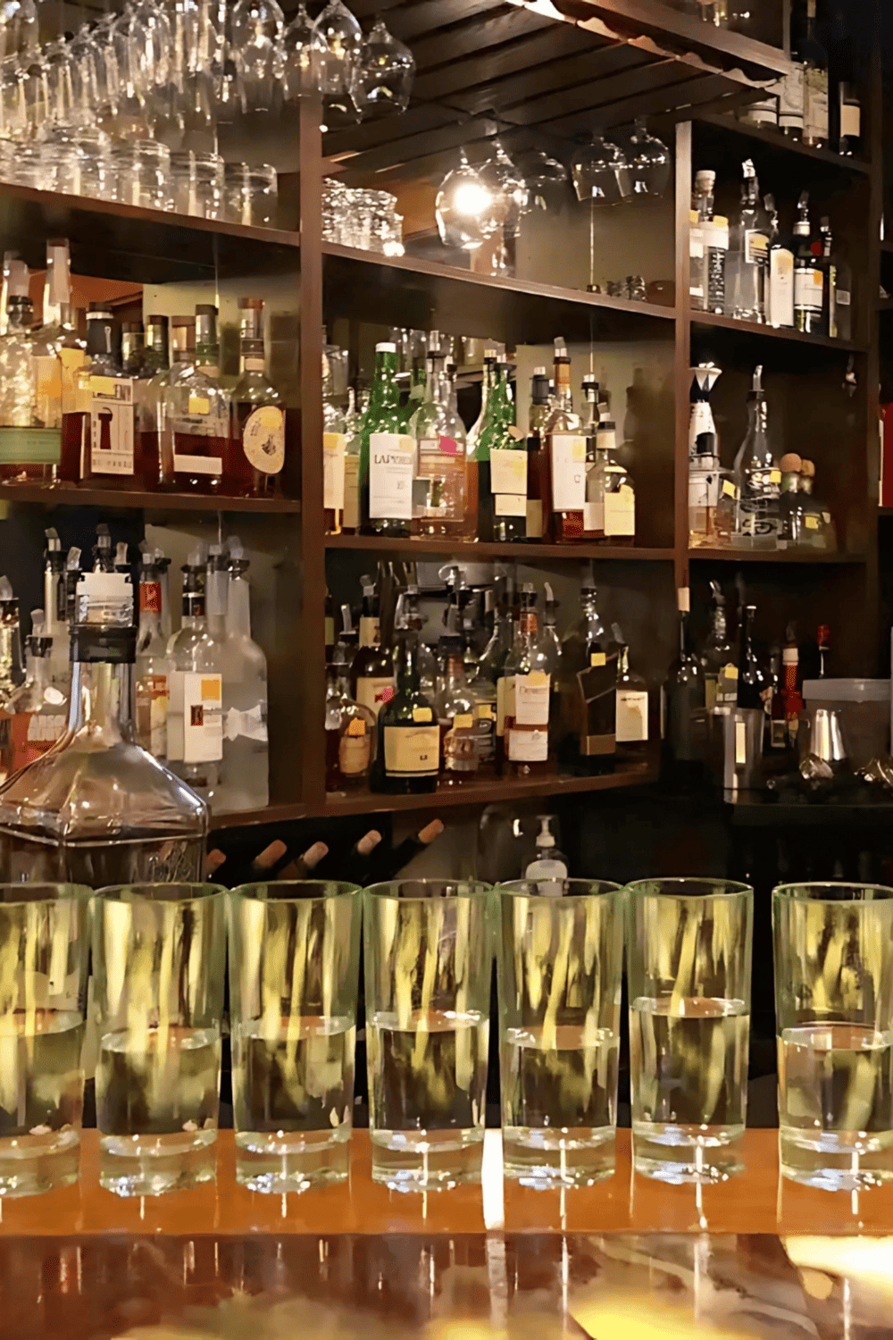 1. Well-stocked bar with liquor bottles, glassware, and bar tools in a cozy setting.