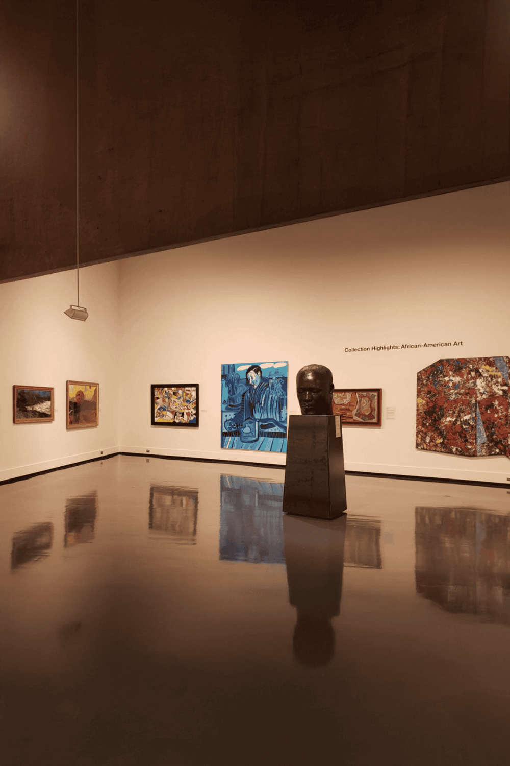Vibrant African-American artwork displayed in a museum gallery with reflective floors.