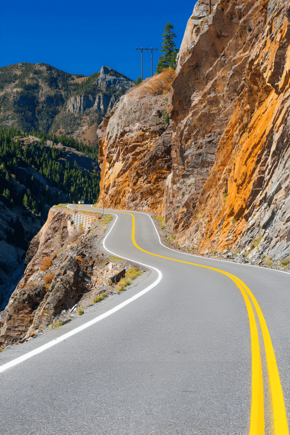 Winding mountain road through cliffs and scenic landscape with clear blue sky, perfect for travel planning and navigation.