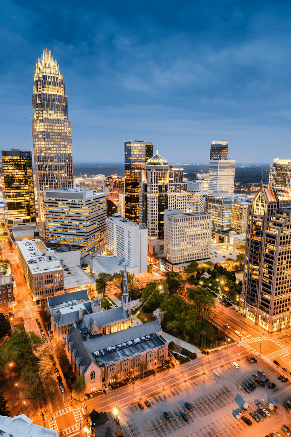 Skyscrapers and cityscape of Charlotte, North Carolina, at twilight with illuminated buildings and streets.
