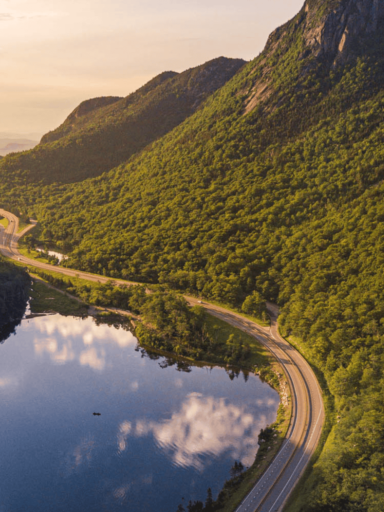 Serene mountain landscape with winding road and lake, scenic nature travel destination, beautiful outdoor scenery.