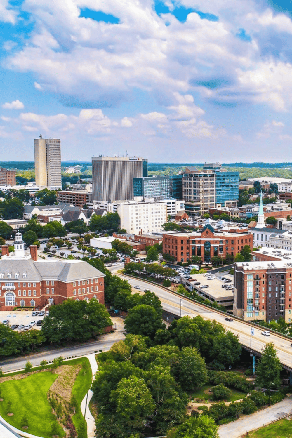 Vibrant city skyline featuring modern buildings and lush green parks under a partly cloudy sky.