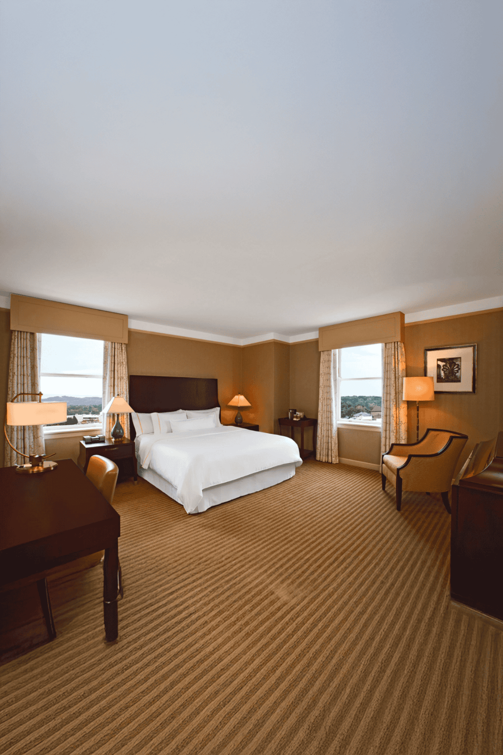 Comfortable hotel bedroom with king-sized bed and scenic city views, featuring cozy lighting and modern decor.