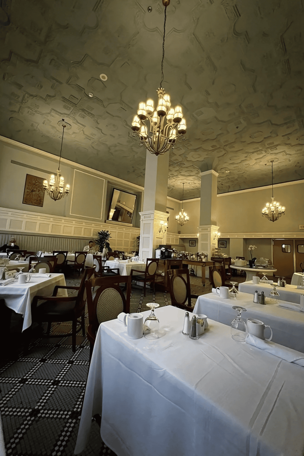 Elegant restaurant interior with chandeliers, white tablecloths, and cozy dining atmosphere for memorable meals.