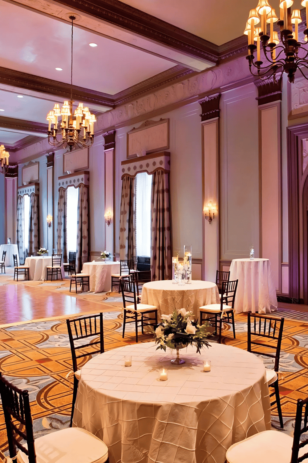 Elegant banquet hall with round tables, floral centerpieces, chandelier lighting, and ornate decor for special events.