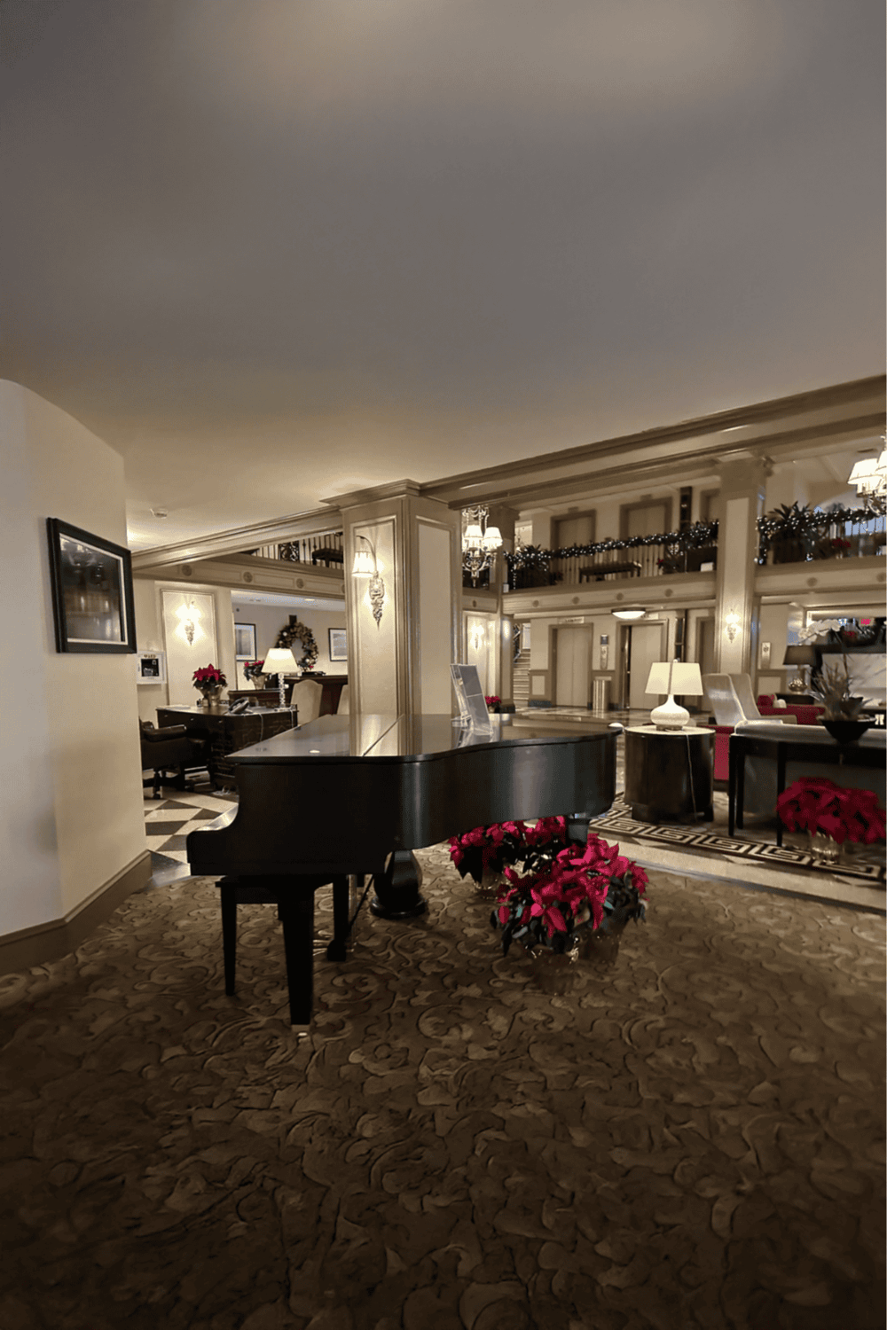 Elegant hotel lobby with grand piano, festive holiday decor, and cozy seating area.