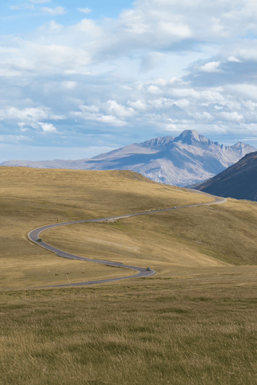 Serene mountain landscape with winding road, blue sky, and lush green hills for travel directions.