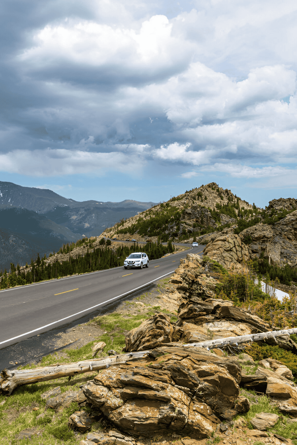 1. Scenic mountain highway with cars driving through rugged terrain and cloudy sky.