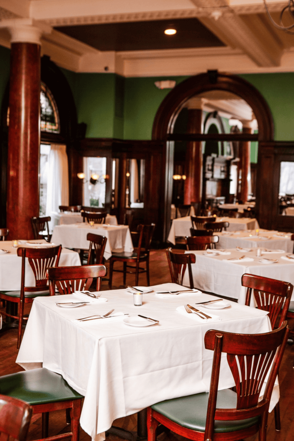 Cozy restaurant interior with white tablecloths, wooden chairs, and elegant decor.
