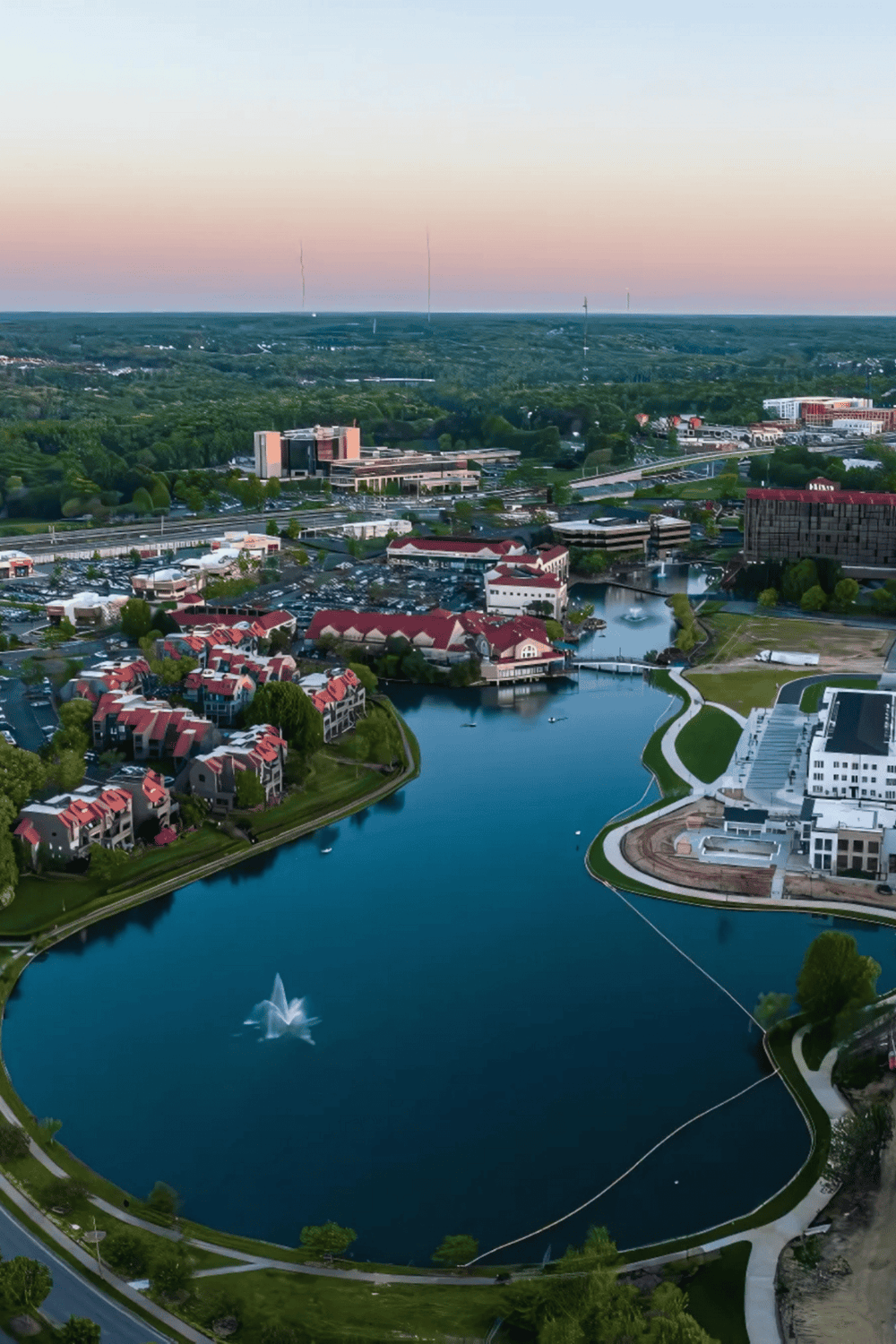 Beautiful aerial view of Quest For Directions campus, featuring a serene lake, modern buildings, and lush greenery.