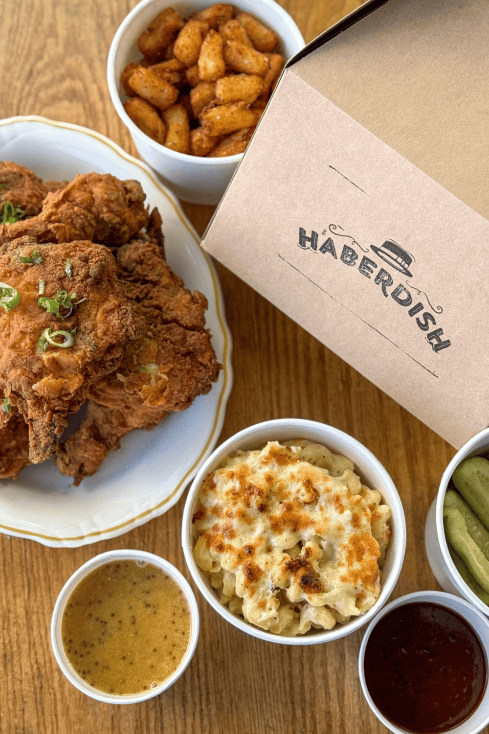 Crispy fried chicken with mac and cheese, potato wedges, and sides at a food delivery restaurant.