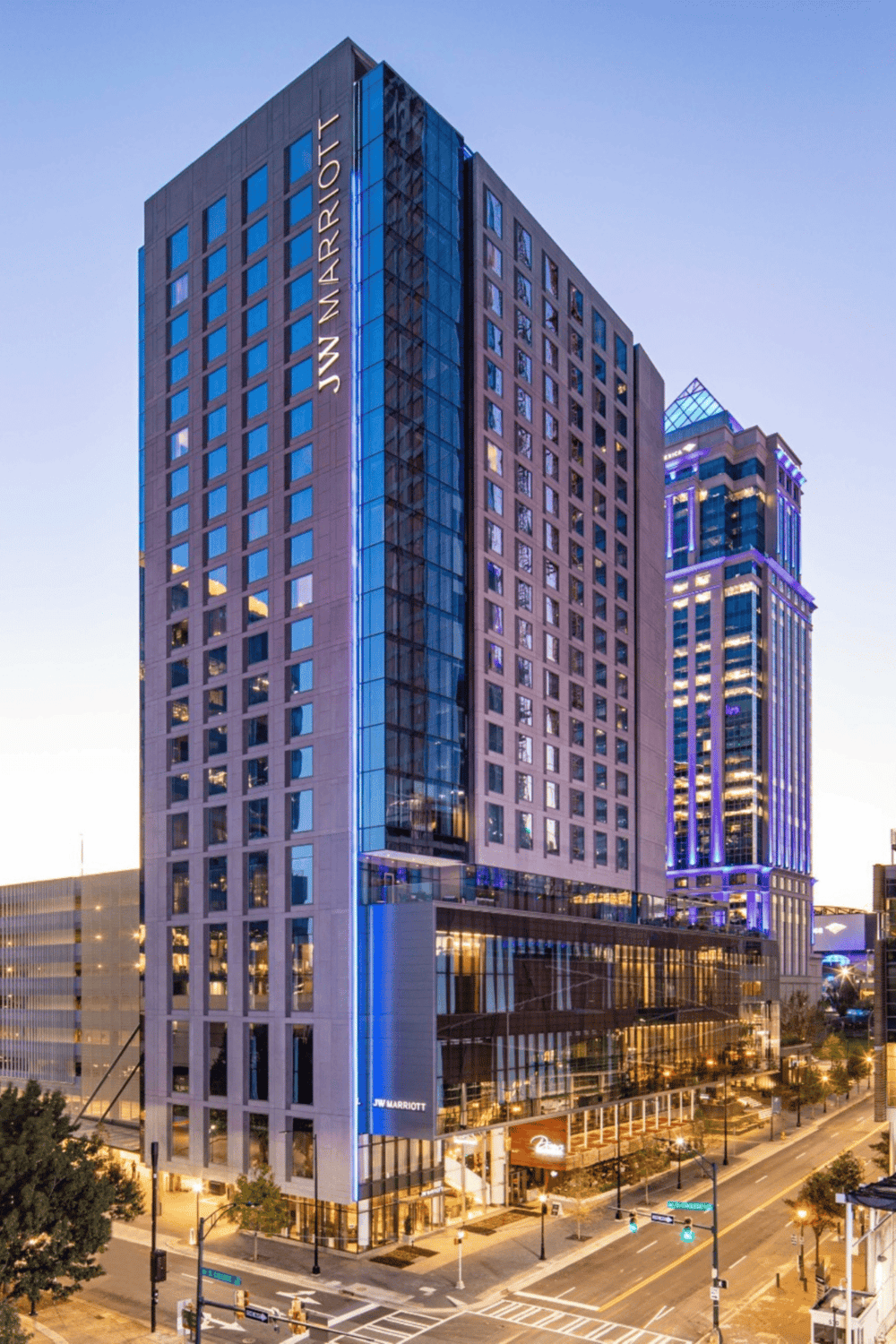 Contemporary JW Marriott hotel building at dusk in downtown cityscape, illuminated with vibrant blue lighting.