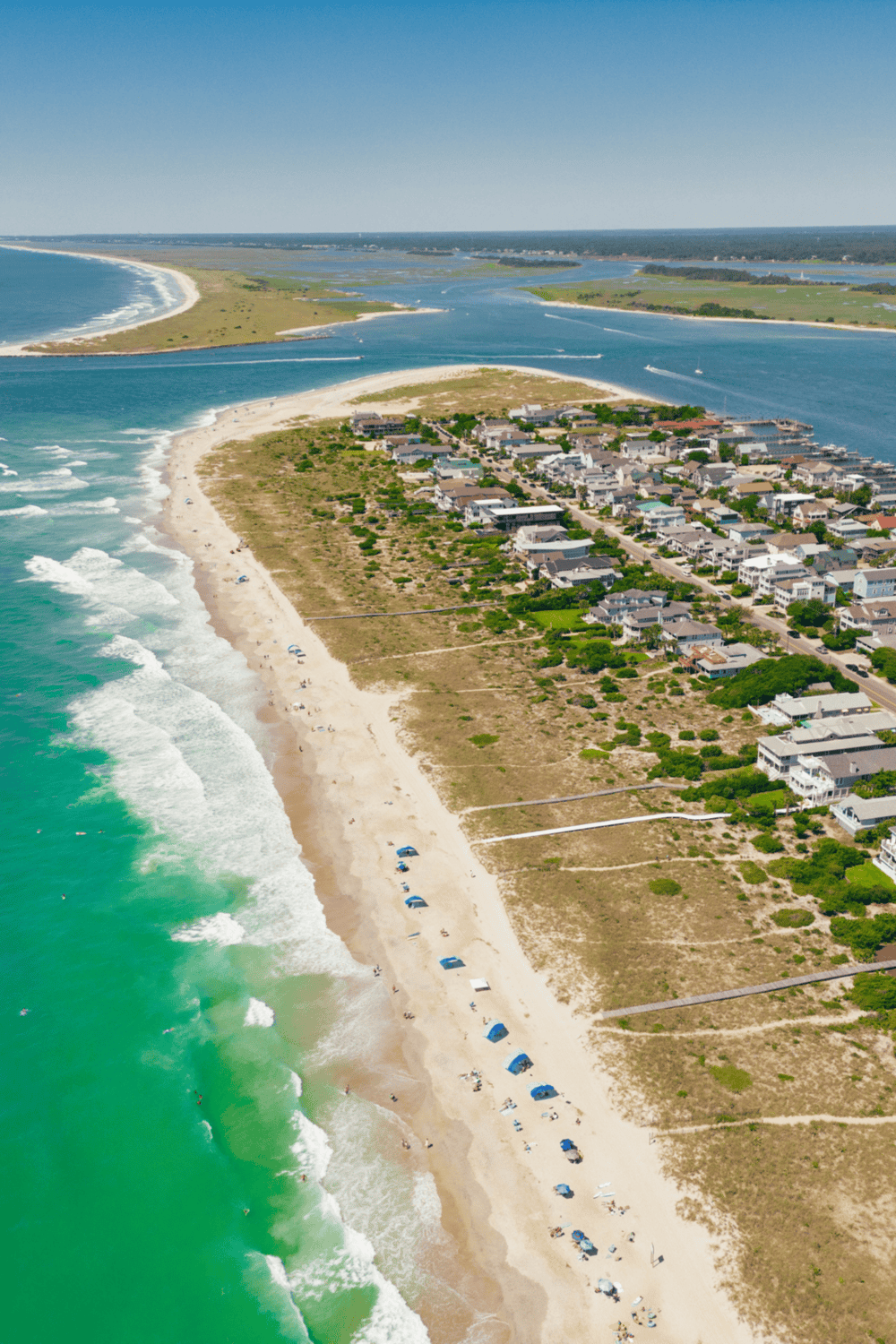Colorful coastal beach scene with ocean waves and beachfront houses.
