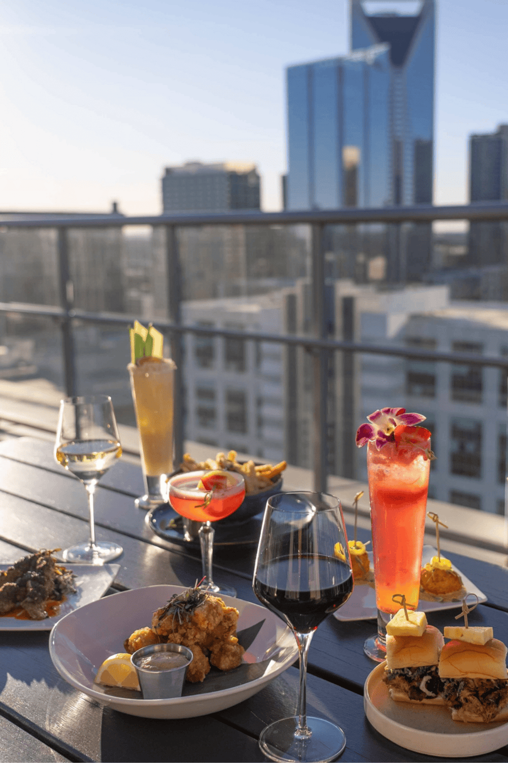 Relaxing rooftop dining with cocktails and appetizers overlooking city skyline.