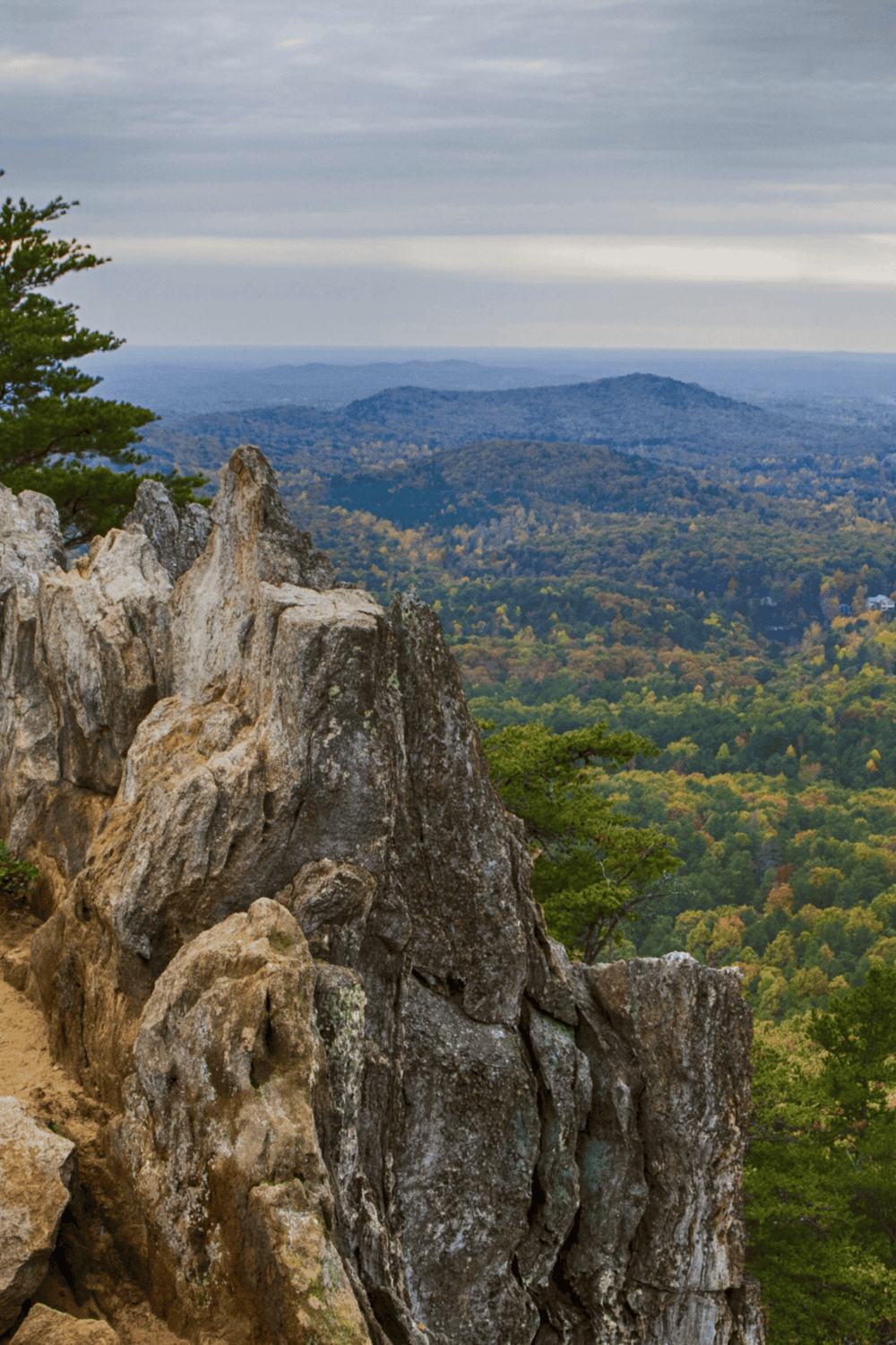 Scenic mountain view with rugged rocks, lush green forest, and rolling hills at QuestForDirections.