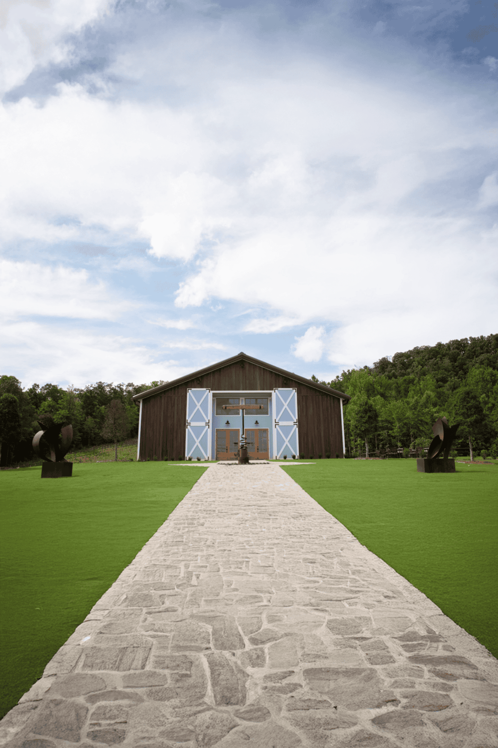 Stunning barn event venue with scenic outdoor setting and modern sculptures for memorable occasions.
