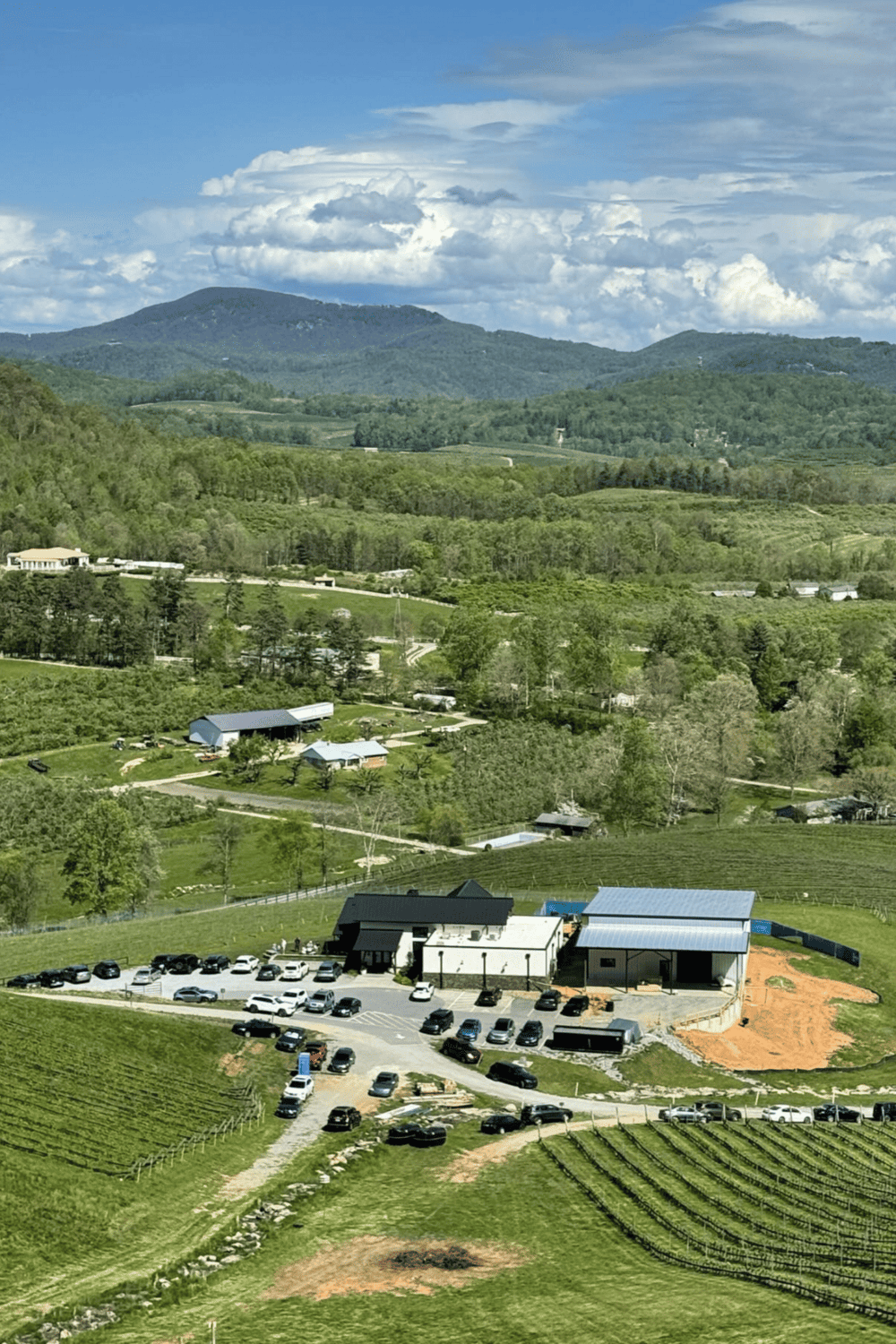 Open landscape with mountains, vineyards, and modern facilities in a scenic rural area.