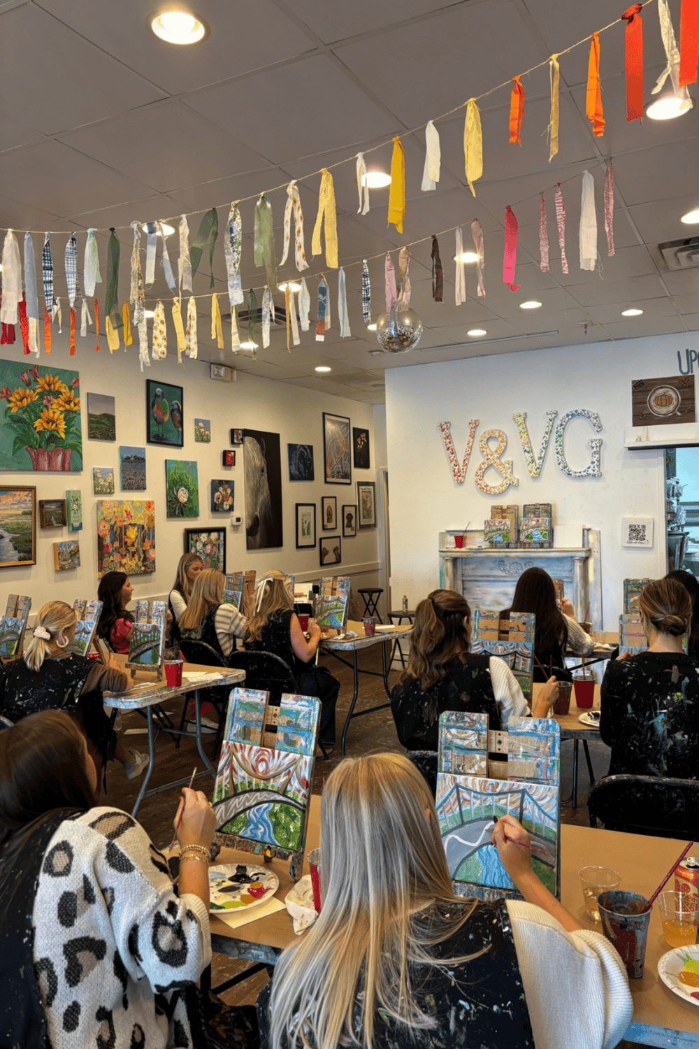 Vibrant art studio with children painting and colorful artwork displayed on walls, perfect for team-building and creative activities.