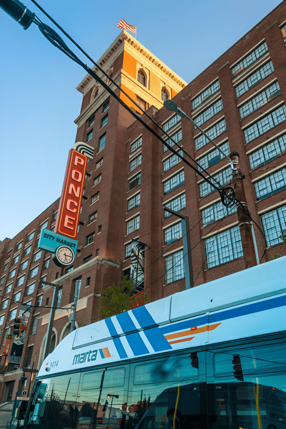 Historic downtown Ponce city building with bus, city market sign, and clear blue sky.