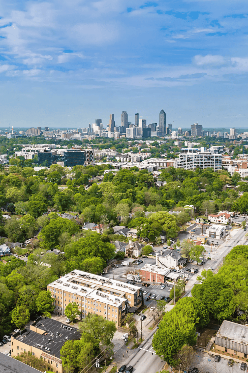 Aerial view of downtown city skyline with green residential neighborhood in foreground.
